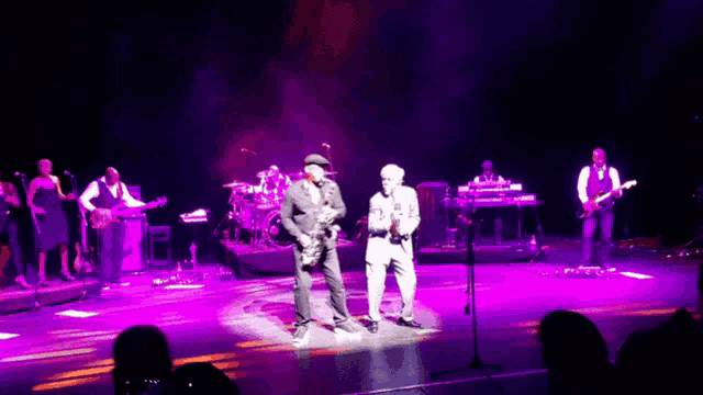 a group of men are on stage with purple lights behind them