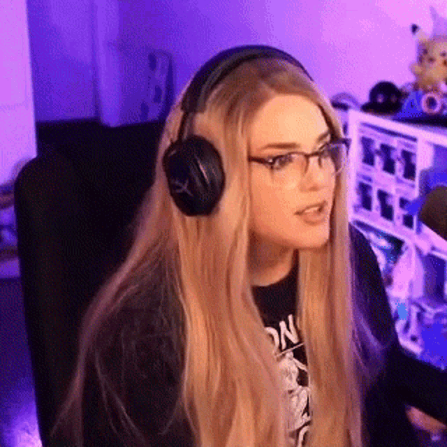 a woman wearing headphones and glasses is sitting in front of a microphone in a room .
