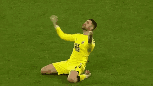 a soccer player is kneeling on the field with his arms outstretched .