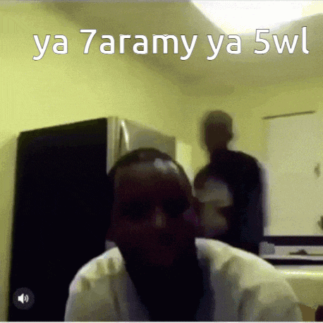 a man sitting in front of a refrigerator with the words ya 7aramy ya 5wl on the bottom