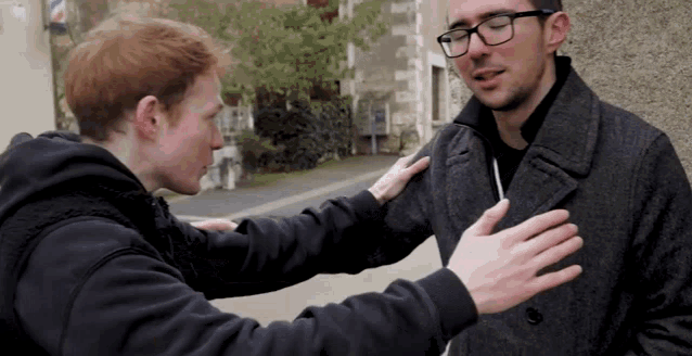 a man with glasses is talking to another man in a black jacket