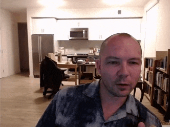 a bald man is standing in front of a kitchen