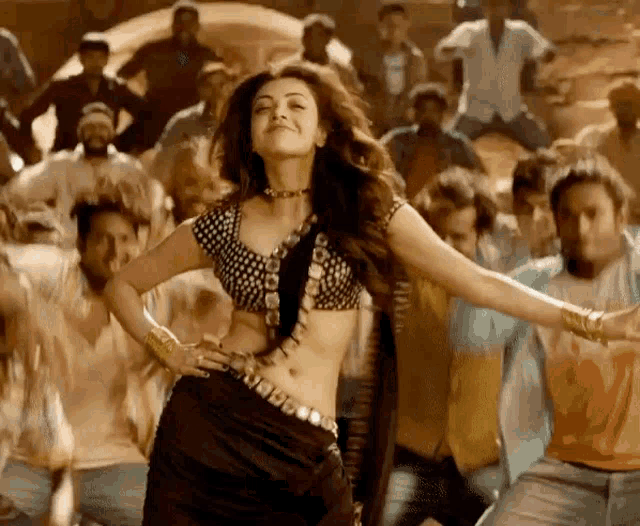 a woman in a crop top is dancing in front of a group of people .