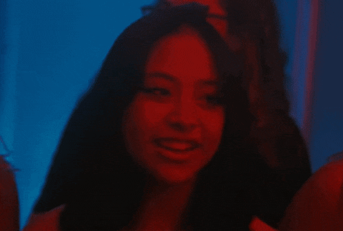 a woman is smiling in a dark room with red lights behind her