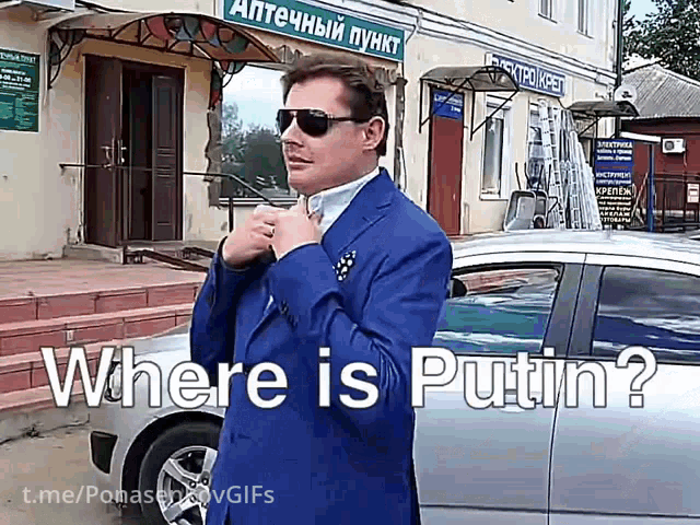 a man in a blue suit and sunglasses is standing in front of a building that says where is putin on it
