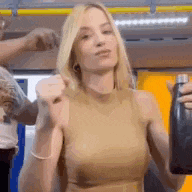 a woman in a tan tank top is holding a black bottle of water .