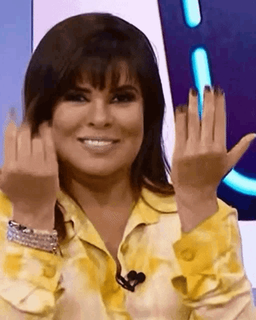 a woman in a yellow shirt is making a funny face with her hands up
