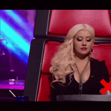 a blonde woman is sitting in a red chair