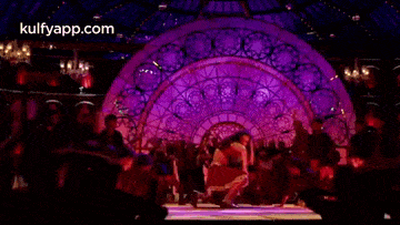 a woman is laying on her stomach on a stage in front of a crowd .