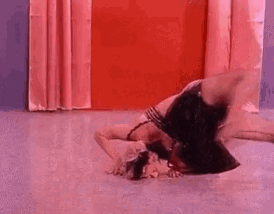 a woman is laying on her stomach on the floor in a room with pink curtains .