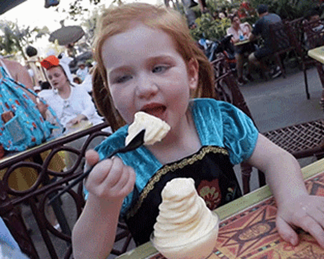 a little girl eating ice cream with a spoon