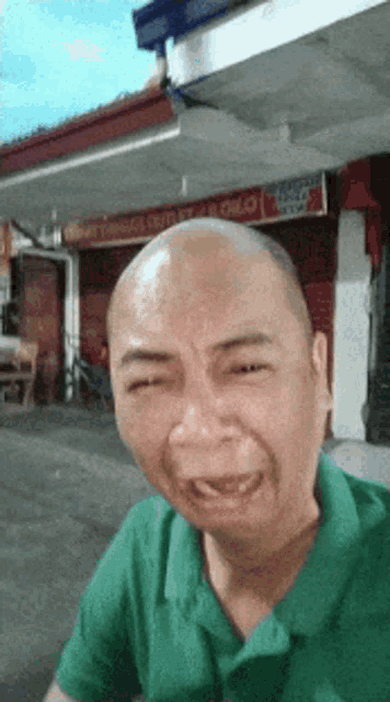 a man in a green shirt is making a funny face in front of a store that says pollo