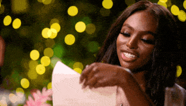 a woman is smiling while holding a piece of paper in her hand