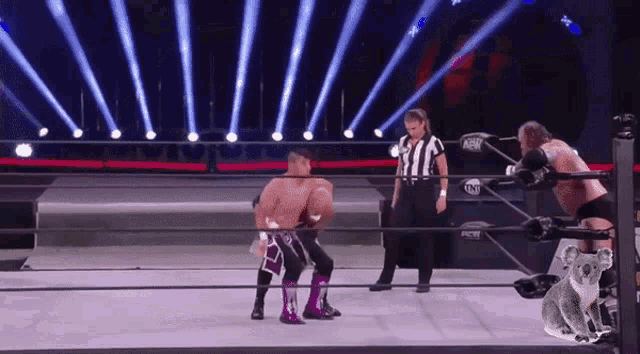 a referee stands between two wrestlers in a ring that says aew