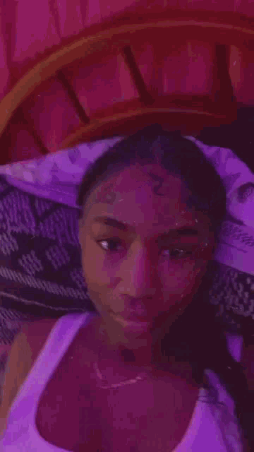 a woman in a white tank top is laying on a bed in a purple room .