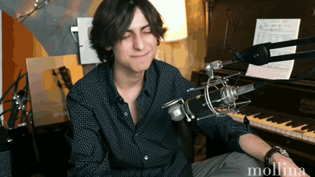 a man sitting in front of a microphone with the name mollina on the bottom right