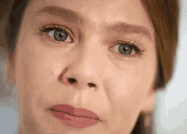 a close up of a woman 's face with tears running down her cheeks .