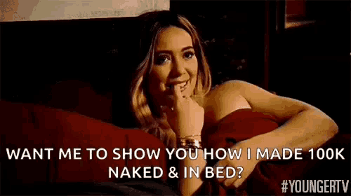 a woman is sitting on a bed covered in a red blanket and talking to someone .