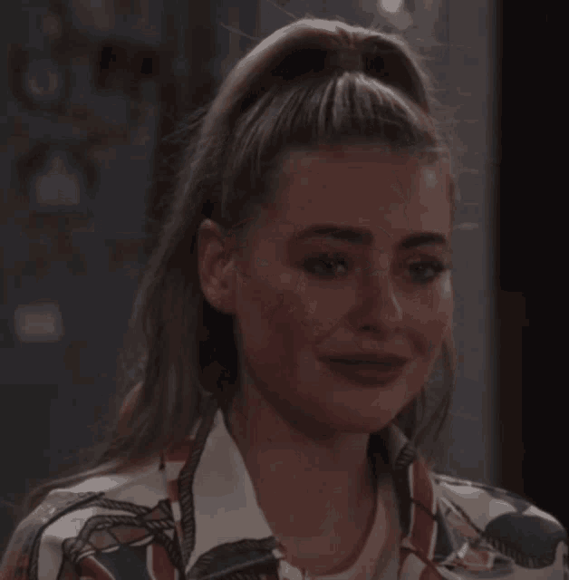 a woman with her hair in a ponytail is looking at the camera
