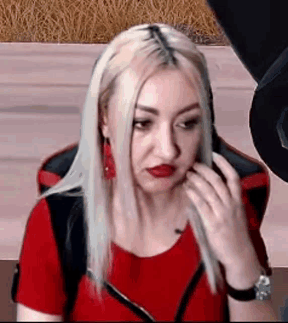 a woman wearing a red shirt and headphones is sitting in a red chair .