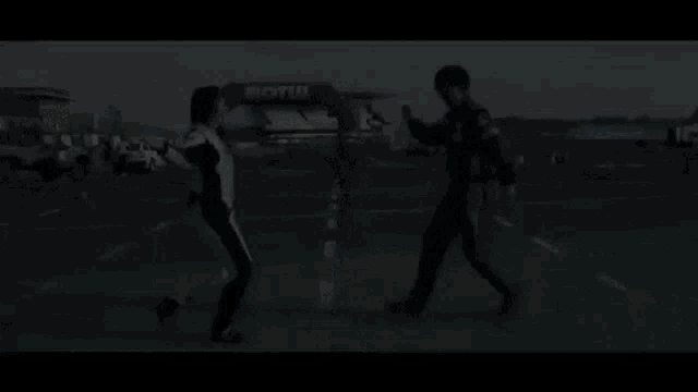 a man and a woman are dancing on a road in front of a race track .