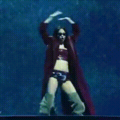 a woman in a crop top and shorts is dancing with her arms in the air