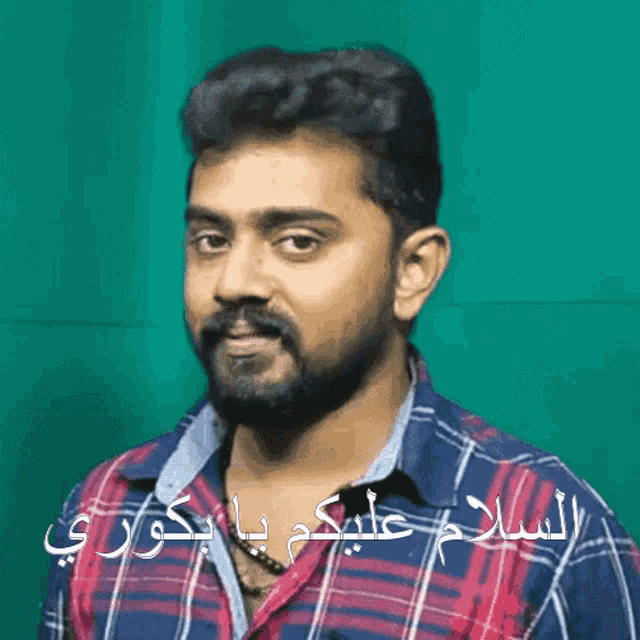 a man with a beard wearing a plaid shirt has arabic writing on his shirt