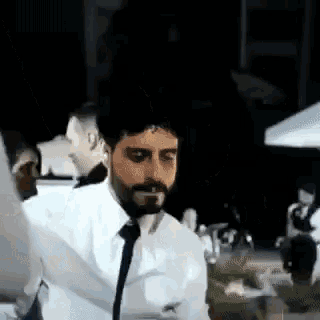 a man with a beard wearing a white shirt and tie is dancing .