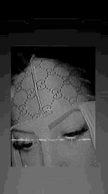 a black and white photo of a woman wearing a gucci bandana on her head .