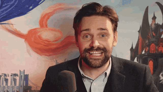 a man with a beard stands in front of a microphone with a castle in the background