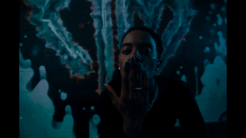 a man with a ring on his finger is smoking a cigarette in a dark room