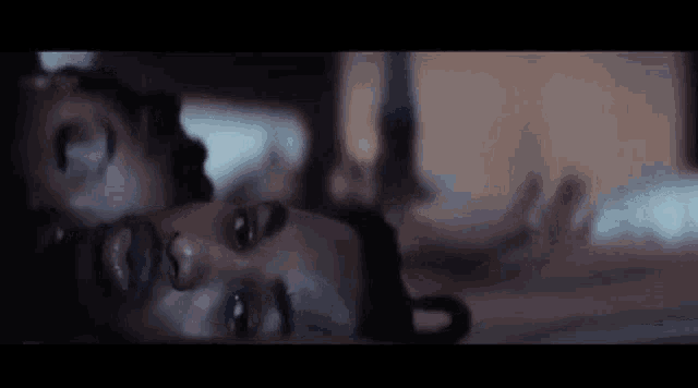 a man and a woman are laying on top of each other on a bed in a dark room .