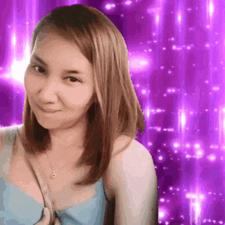 a woman is smiling in front of a purple background with sparkles
