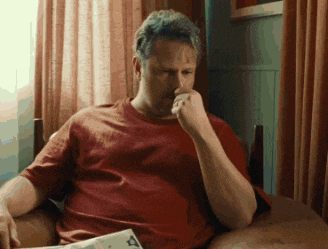 a man in a red shirt is sitting on a couch reading a book