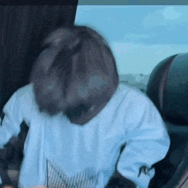a person is sitting in the back seat of a car with their head in their hands .
