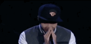 a man in a baseball jacket is covering his face with his hands