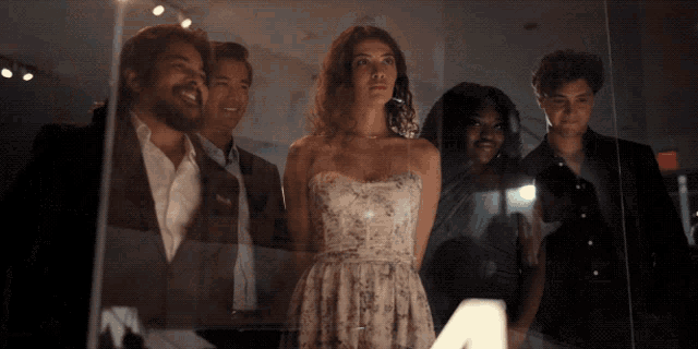 a woman in a white dress stands between two men