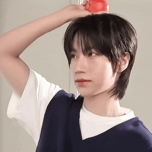 a young boy is holding an apple on his head
