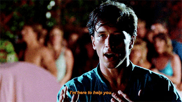 a man says " i 'm here to help you " in front of a crowd of people