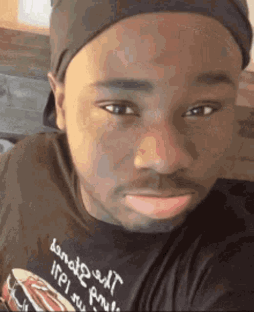 a man wearing a black hat and a black shirt is making a funny face .