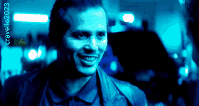 a man is smiling in a blue light with the number cravello2023 on the bottom right