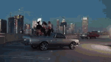 a man is driving a sports car down a highway at night .