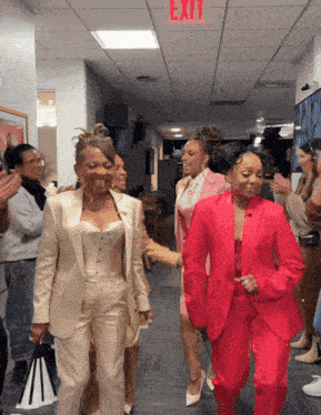 a red exit sign is above a group of women in suits