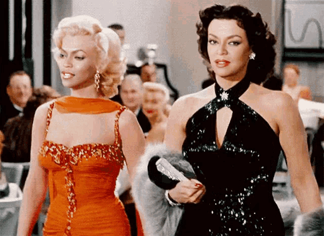two women in dresses are standing next to each other .
