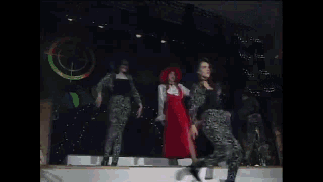 a group of women are dancing on a stage in front of a green sign that says toyota .