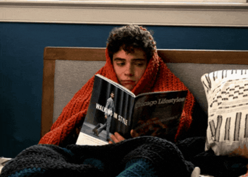 a man wrapped in a red blanket is reading a book titled walking in style