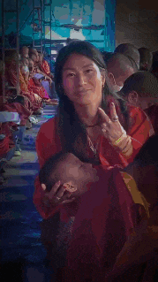 a woman in a red shirt is holding a baby