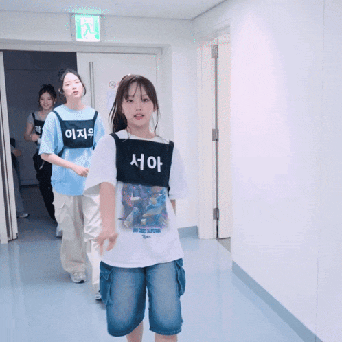 a girl wearing a t-shirt that says ' california ' on it walks down a hallway
