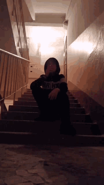 a person sitting on a set of stairs wearing a hoodie that says jacks