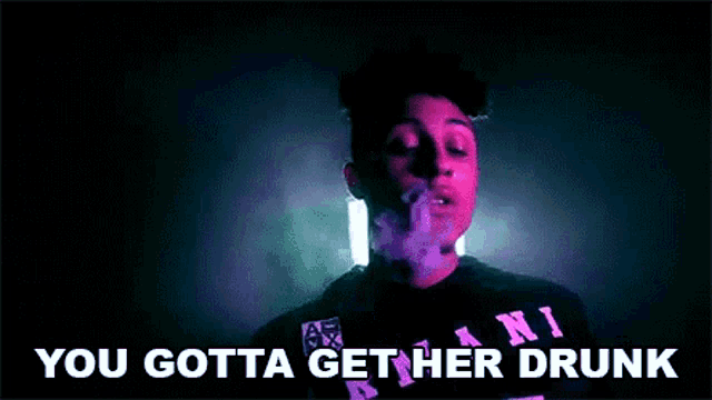 a man is smoking a cigarette in a dark room with the words `` you gotta get her drunk '' written below him .